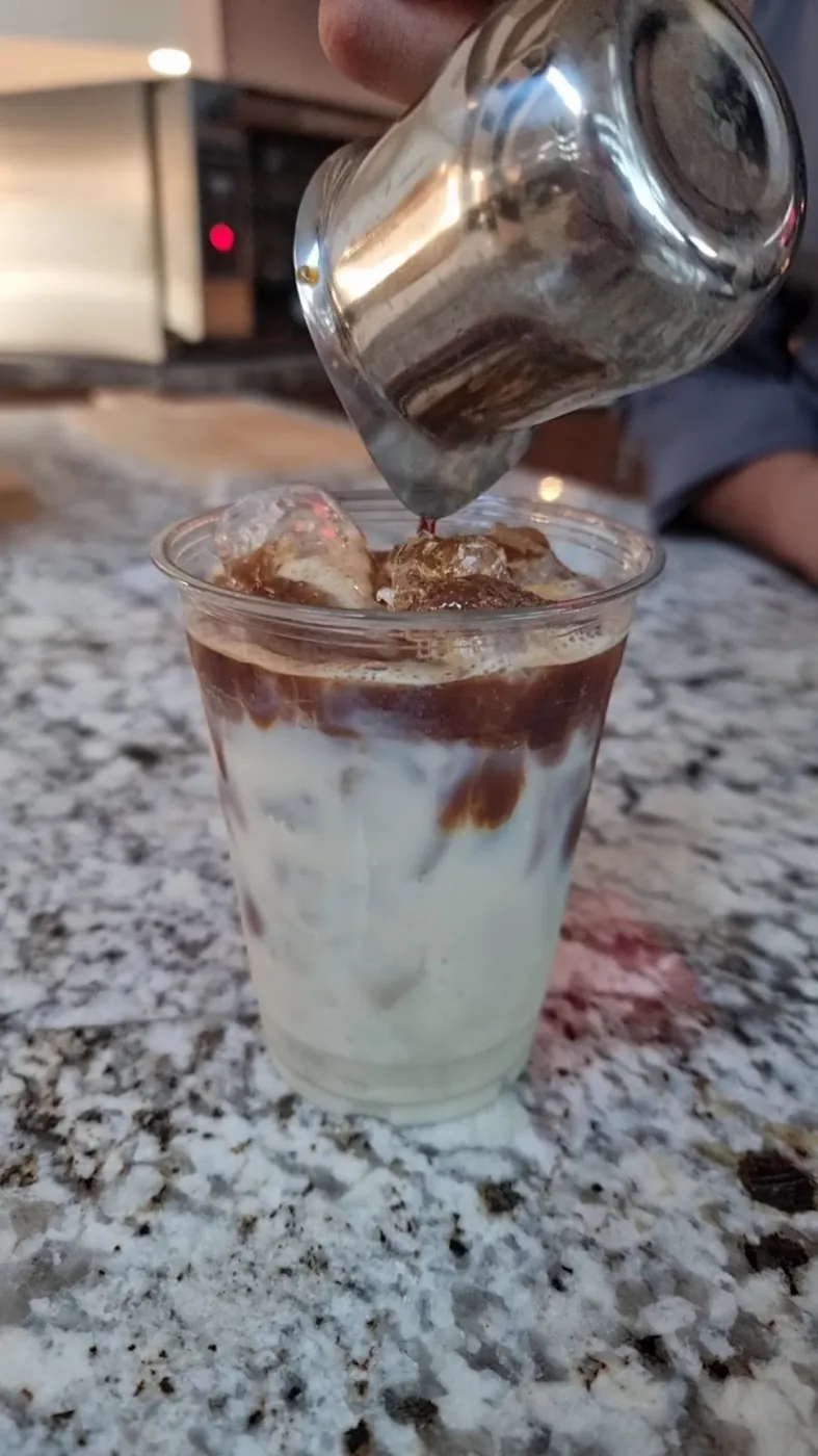 Espresso vertido sobre leche con hielo